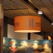 Grote lampenkap boven beursstand, bedrukt met WESTAG logo